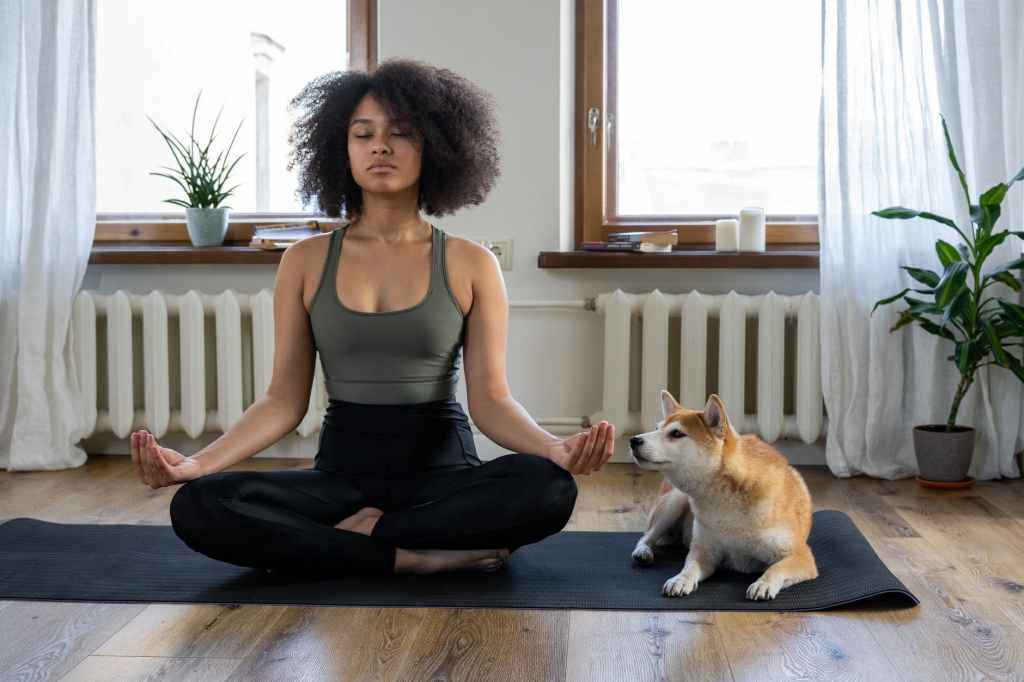 seated young woman meditating with pet dog