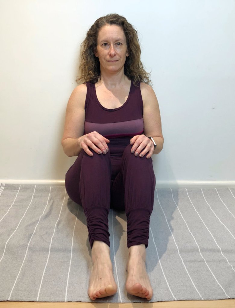woman sitting against wall yoga pose