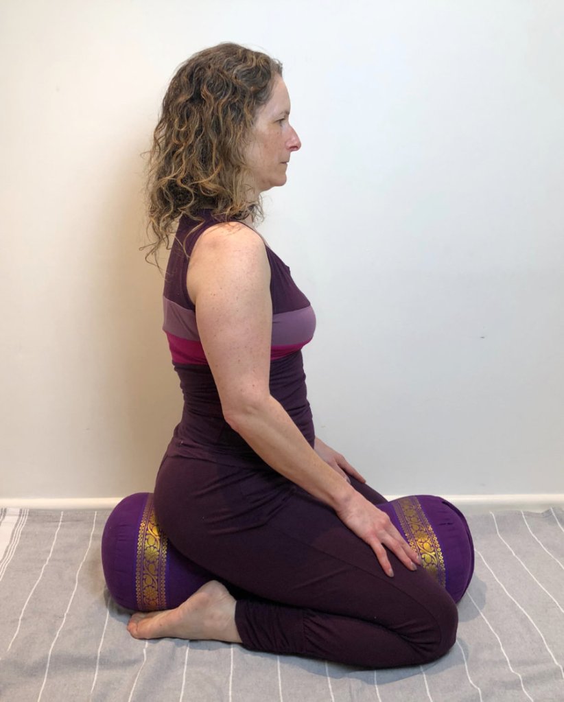 woman kneeling using yoga bolster